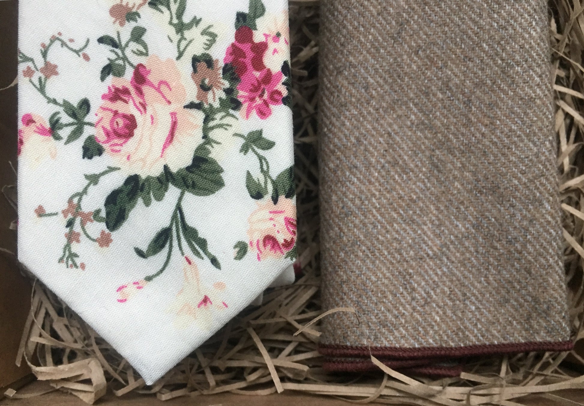 A close up of a blush pink floral men's tie on an ivory background. The tie is matched with a beige wool pocket square. The set comes stunningly gift wrapped and is perfet as a men's gift, wedding tie or groomsmen gift. At Daisy and Oak Studio, we make our ties by hand and offer bespoke products. 